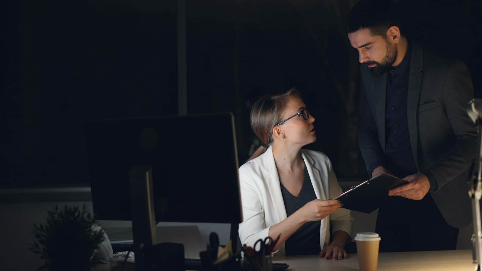 Two colleagues reviewing a document at a desk late in the evening