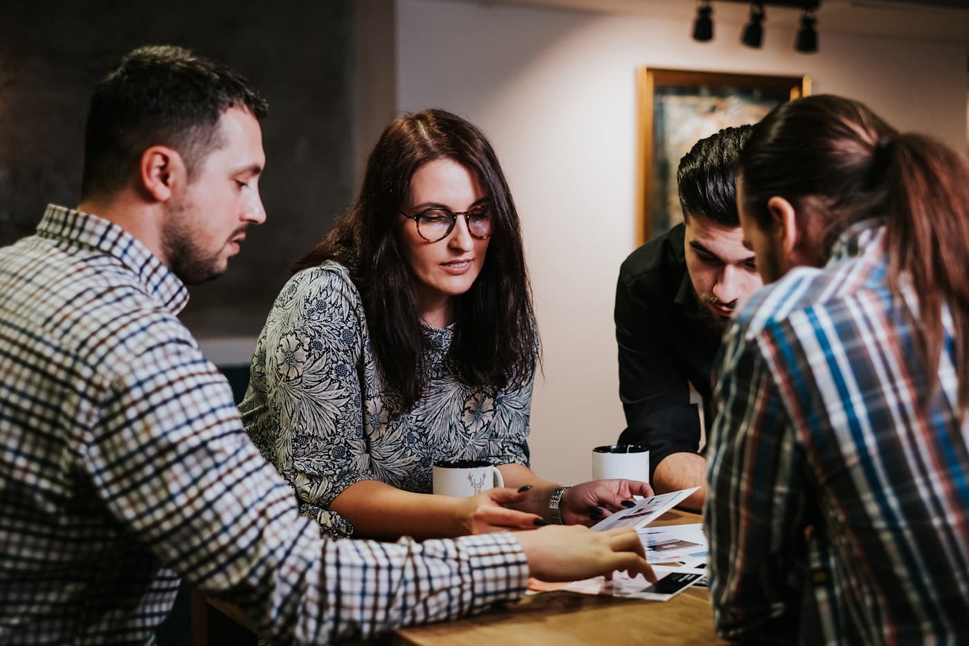 Four colleagues reviewing printed documents around a table