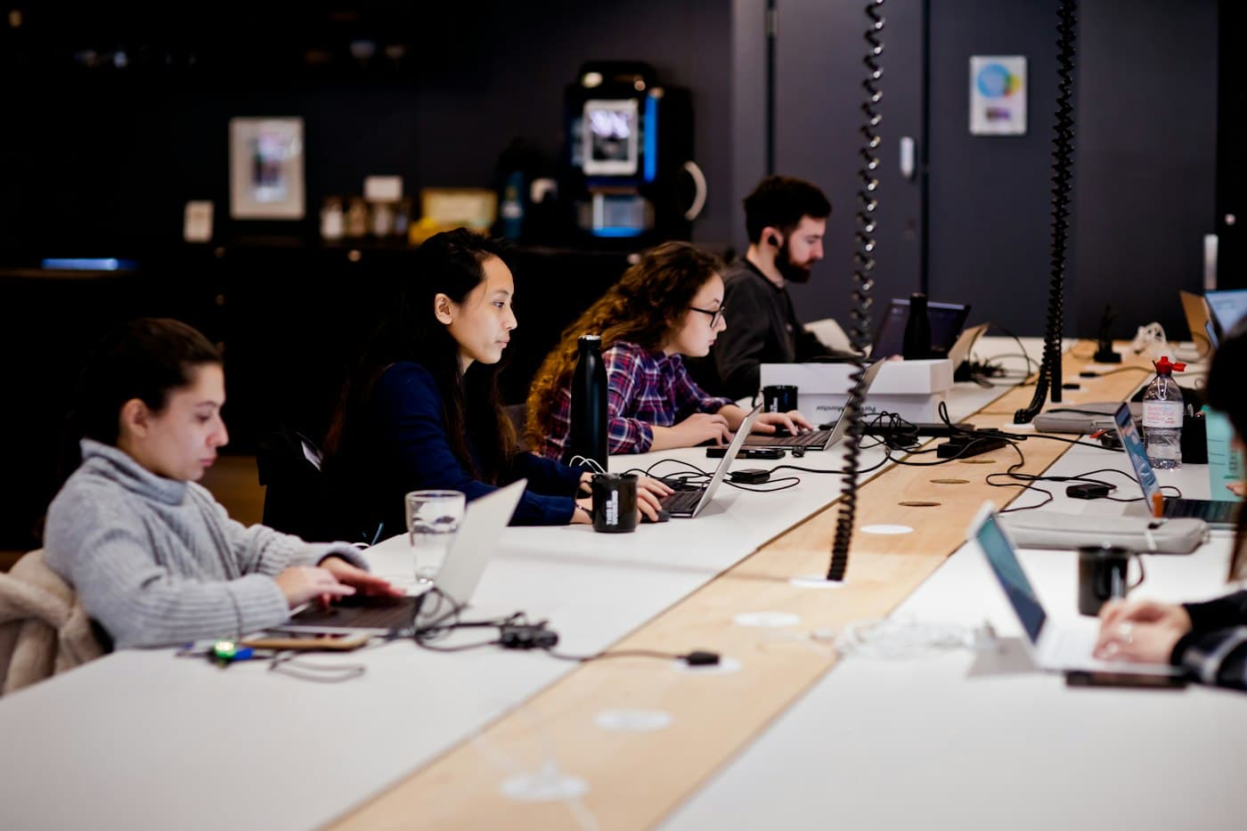 Colleagues working side by side on laptops at a long shared desk